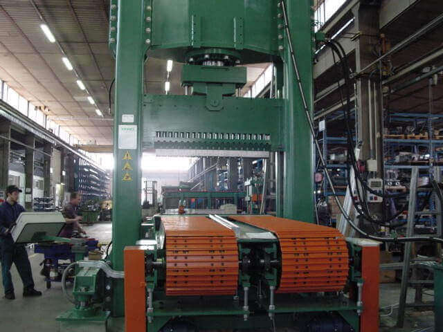 Pressa industriale con nastro trasportatore arancione