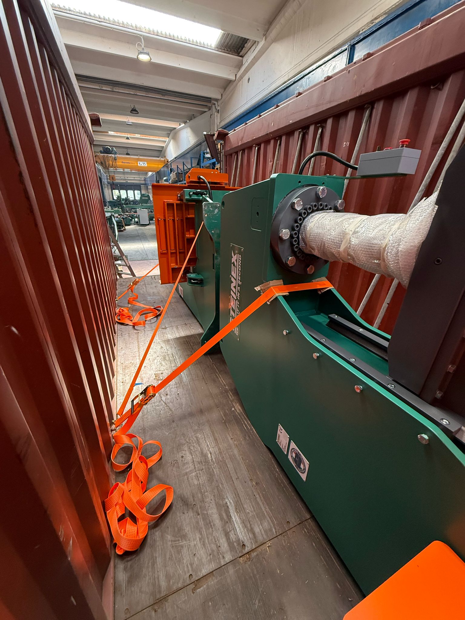 Macchinario industriale verde fissato con cinghie arancioni